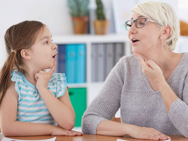 Speech-language pathologist guiding a young girl through fluency practice during stuttering therapy in Apple Valley, CA